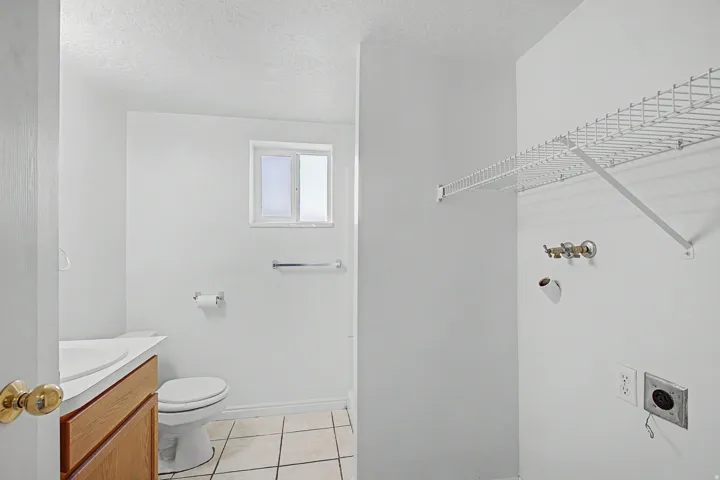 Dedicated utility area featuring a wire storage shelf, laundry hookups, and a window for natural light