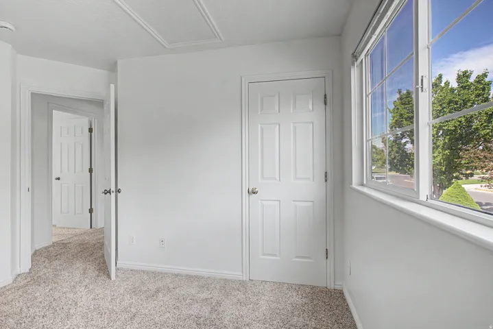 Bright room featuring a large multi-pane window, white trim, and light textured carpeting
