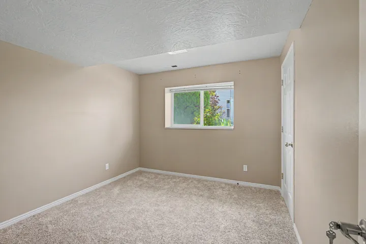 Carpeted room featuring a single window and a paneled door