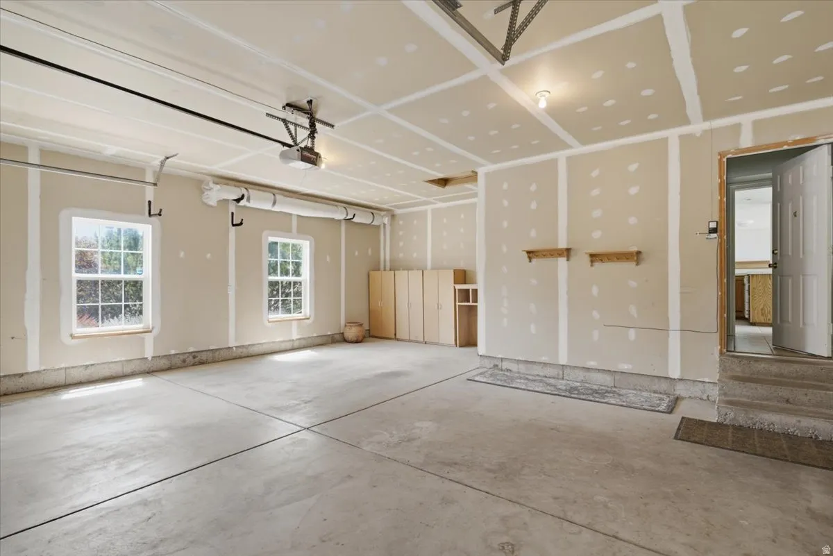 Spacious garage featuring a concrete floor, two large windows, built-in cabinetry, and overhead lighting
