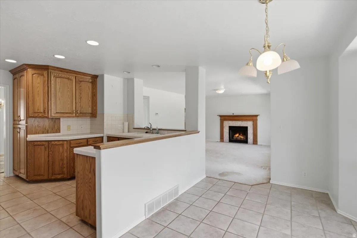 Kitchen featuring warm wood cabinetry, light countertops, and a tiled backsplash