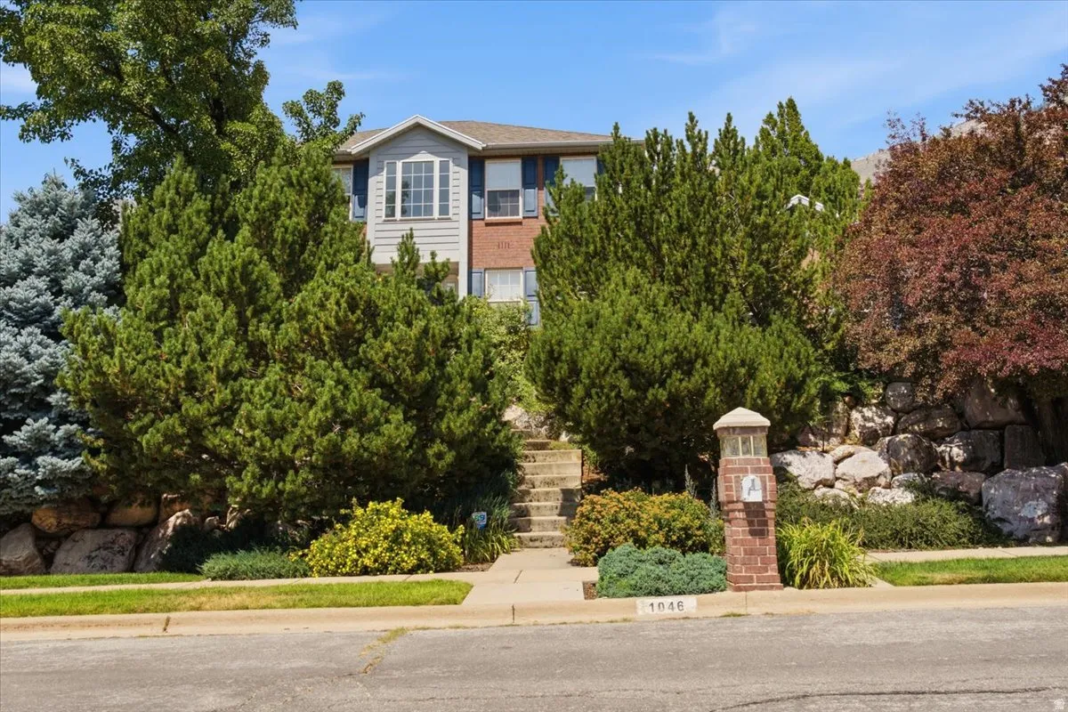 Multi-story residence featuring a bay window, a brick and siding exterior, and blue window shutters