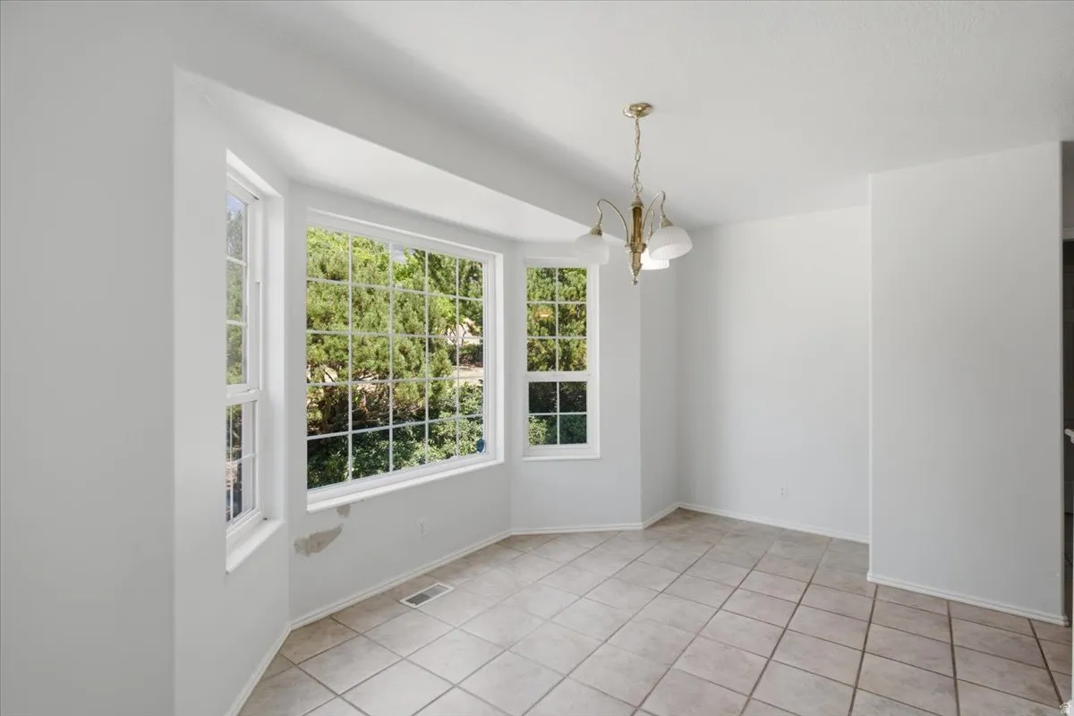 Dining area featuring a bay window, a three-light chandelier, and tile flooring