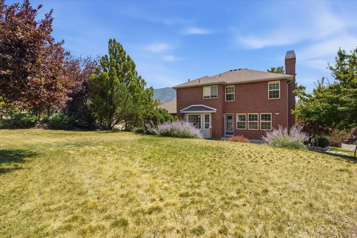Brick exterior residence featuring multiple windows, a rear entry, and a prominent chimney