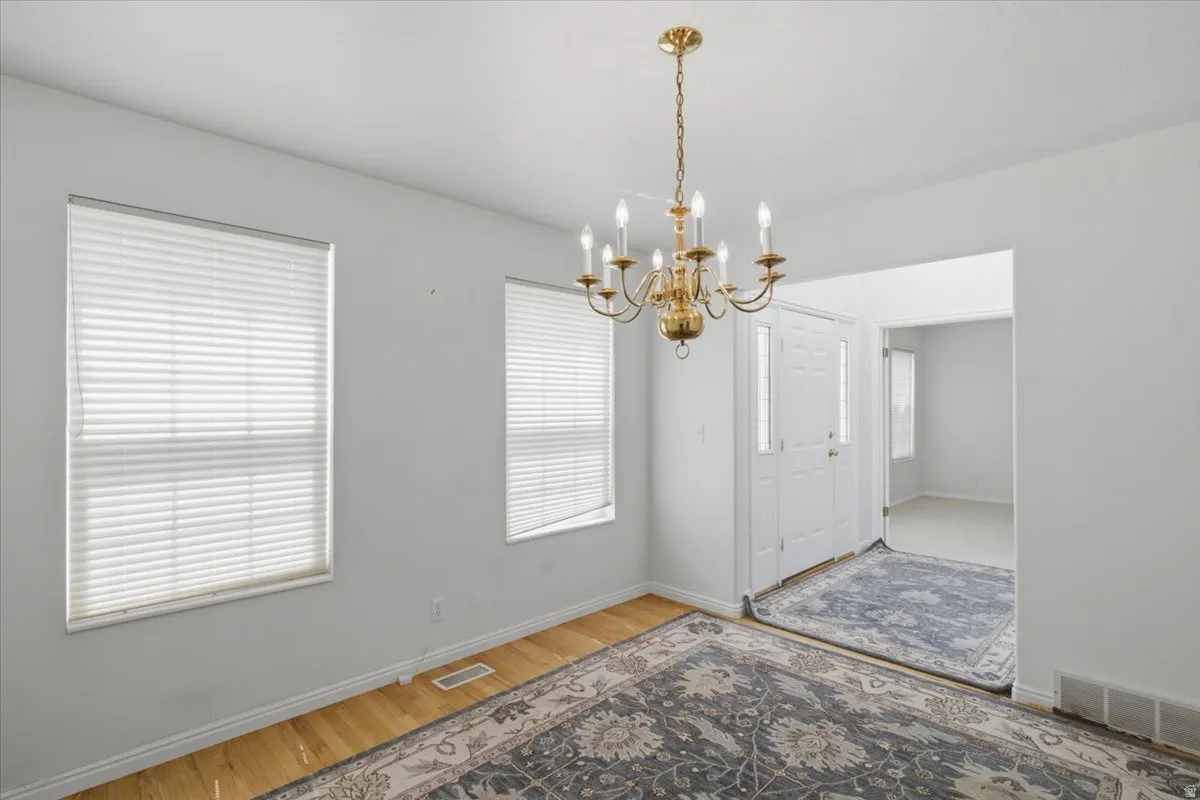 Entryway featuring a decorative brass chandelier, wood-finish flooring, and white interior paint