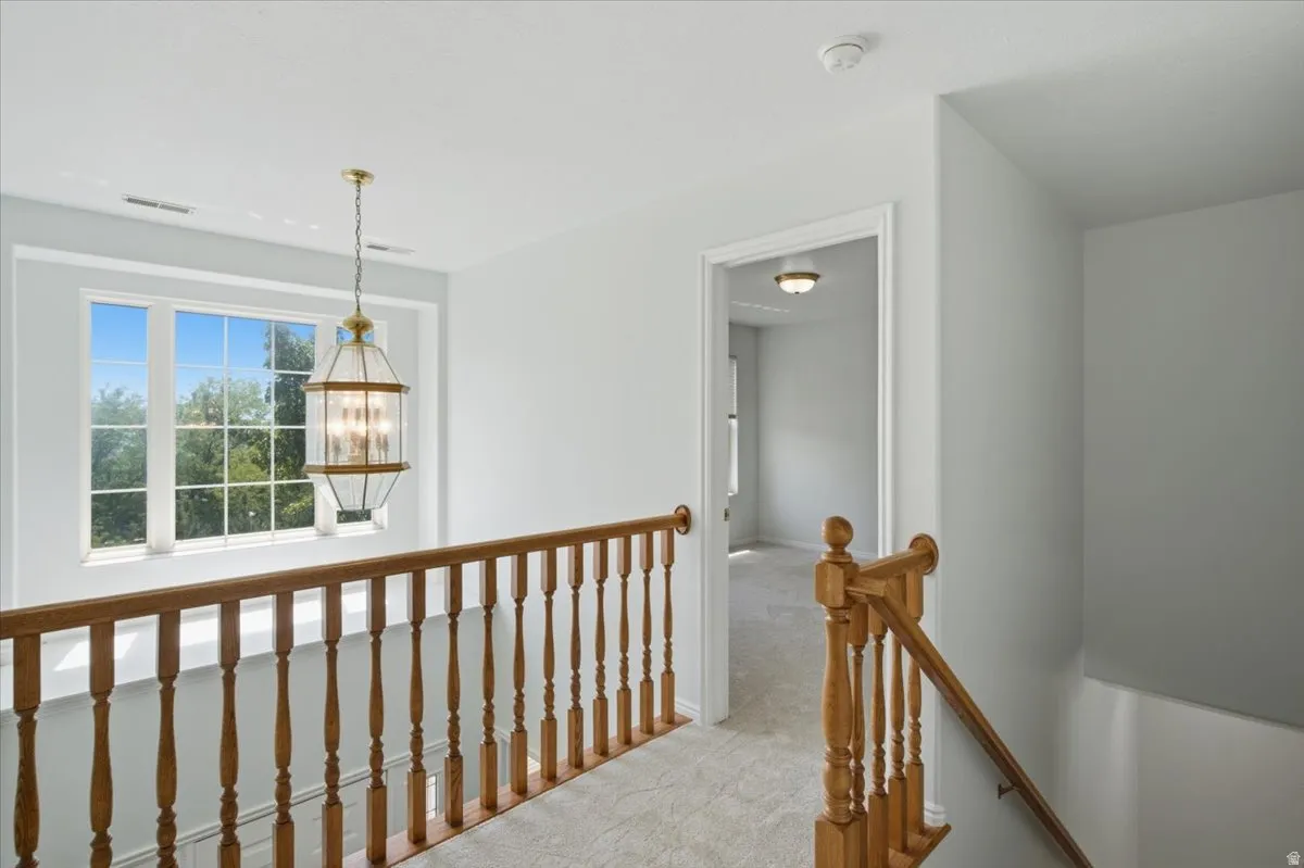 Upper-level landing featuring a wood baluster railing, a large multi-pane window, and a decorative pendant light fixture