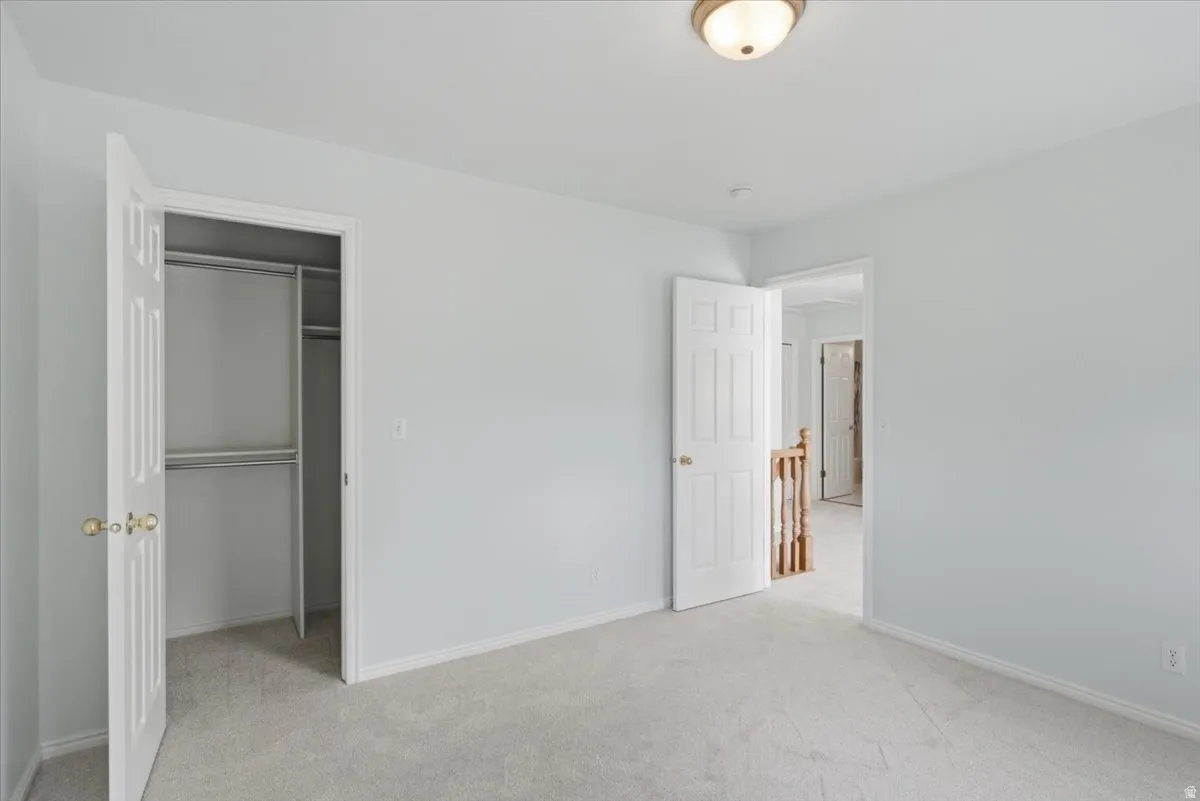 Carpeted room featuring light blue walls, a ceiling-mounted light fixture, white trim, and a bi-fold closet with shelving and hanging rods