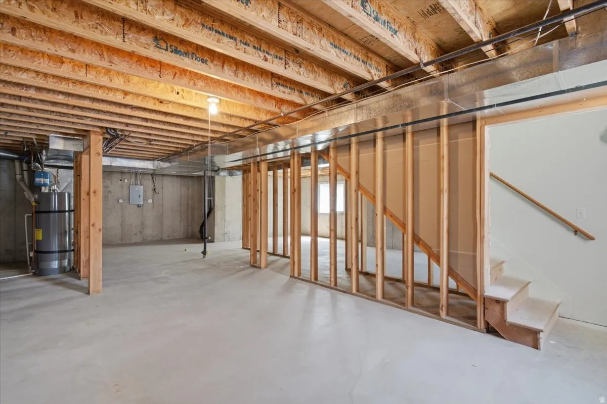 Unfinished lower level featuring exposed wood joists and concrete flooring, offering significant customization potential