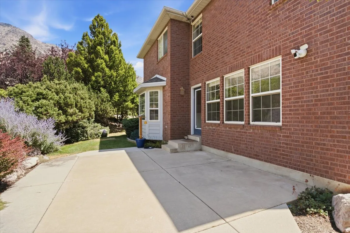 Brick exterior with multiple windows, a bay window, and a concrete patio