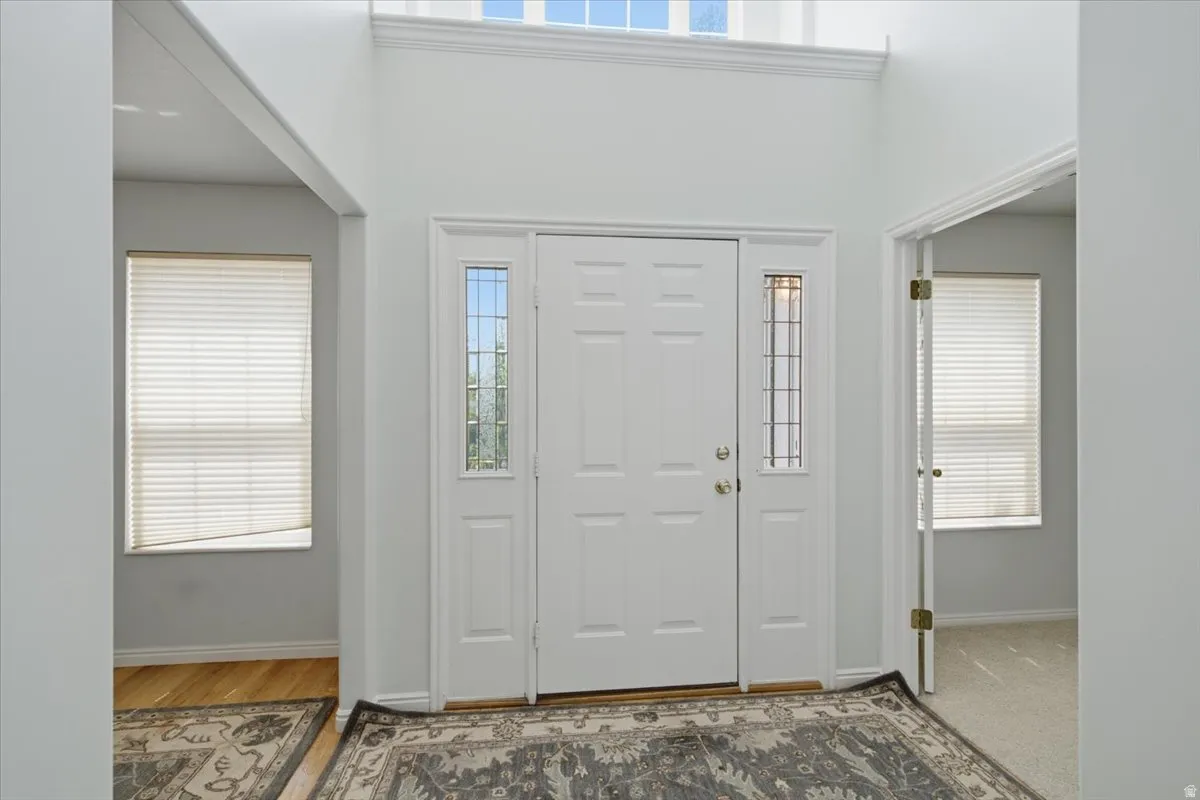 Bright entryway featuring a double door with decorative glass sidelights, a transom window, and a vaulted ceiling