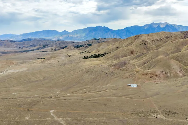 Expansive desert landscape featuring distant mountain ranges and a large structure with a light-colored roof