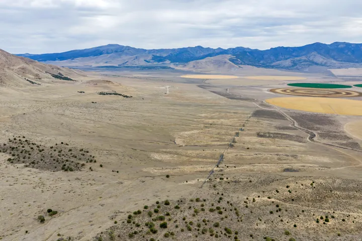 Expansive arid landscape featuring distant mountains and cultivated circular fields