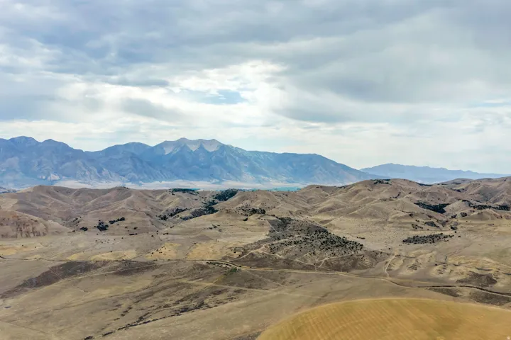 Expansive rolling hills and distant mountain ranges under a partially cloudy sky