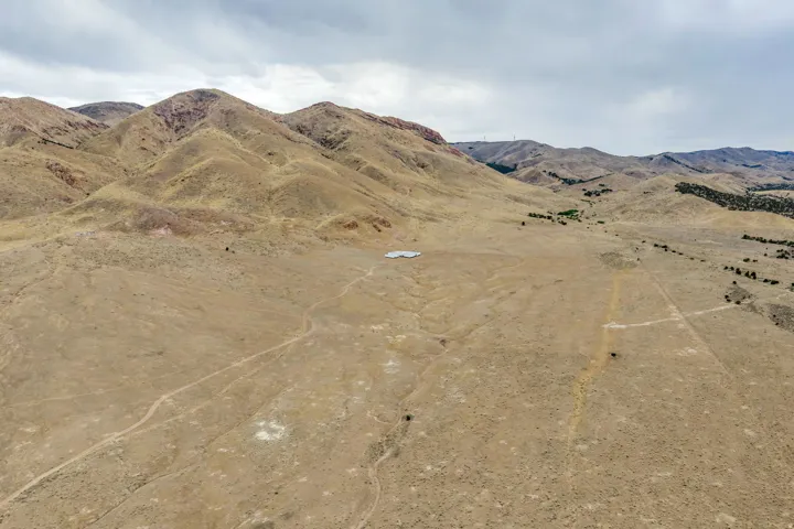 Expansive high desert landscape featuring a distant structure and rolling hills