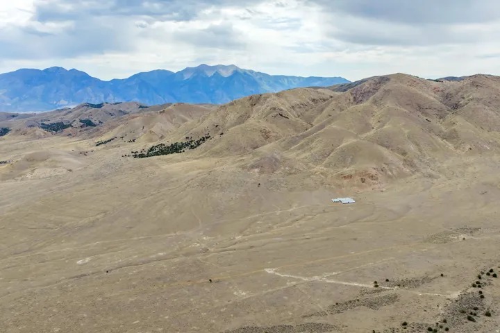 Expansive arid terrain featuring distant mountains and a single structure