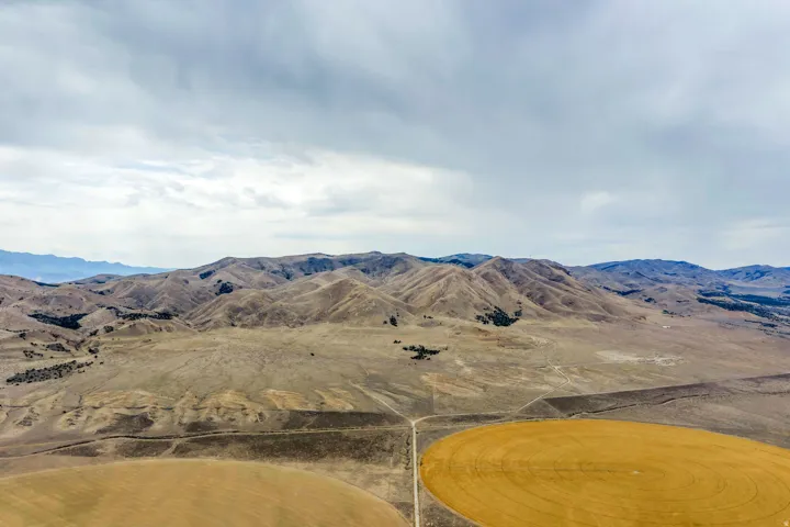 Expansive agricultural land featuring a central circular field and surrounding natural terrain