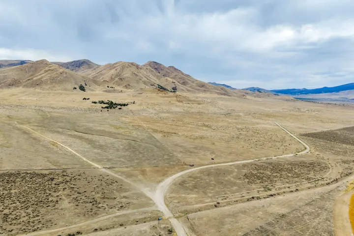Expansive arid landscape featuring rolling hills and distant mountains