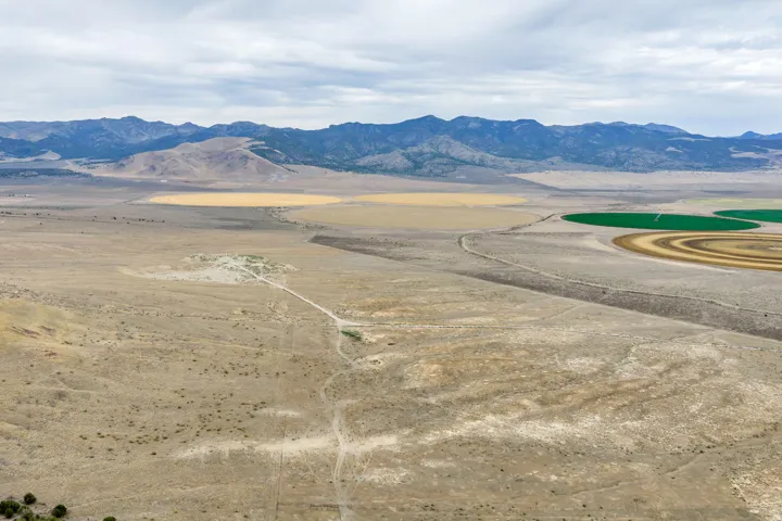 Expansive arid landscape featuring distant mountains and circular agricultural fields