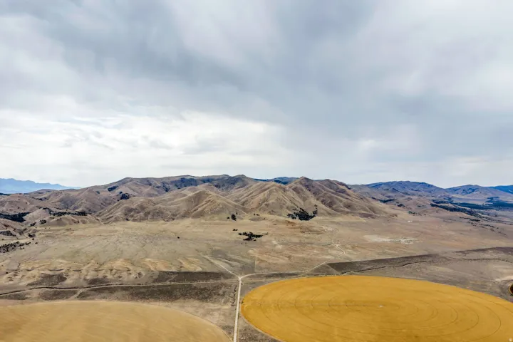 Expansive land parcel featuring mountainous terrain and cultivated circular fields