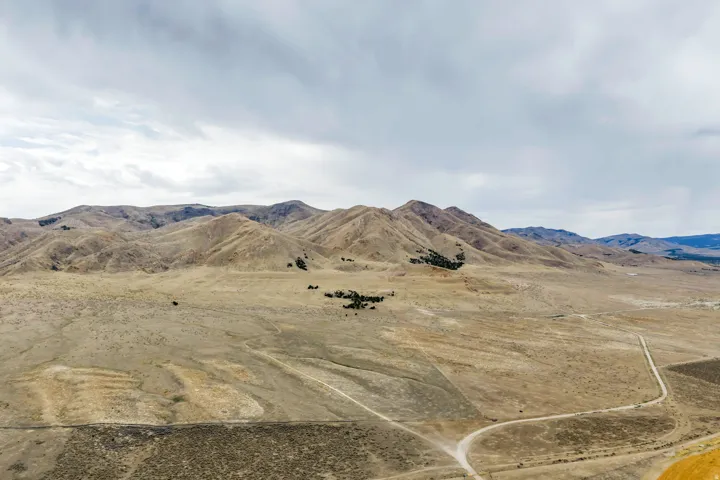 Expansive arid landscape featuring rolling hills and distant mountains