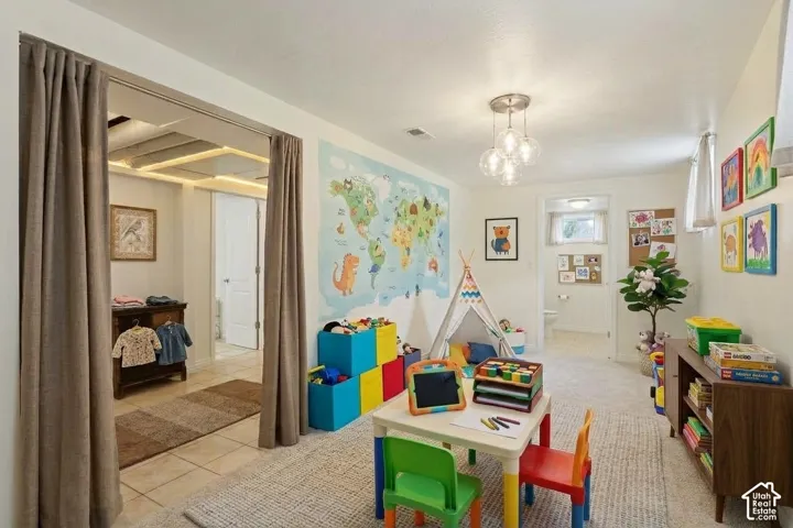 Interior room featuring neutral wall-to-wall carpeting, a multi-globe glass pendant light fixture, and a walk-through area defined by floor-to-ceiling fabric curtains
