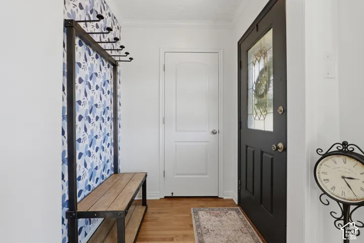 Entryway featuring hardwood flooring, a black front door with decorative glass, and bench with coat hooks