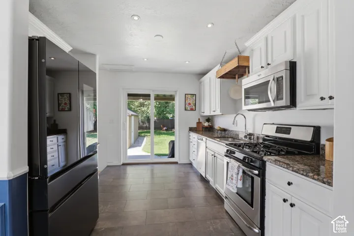 Kitchen featuring white cabinetry, stone countertops, stainless steel appliances, and tile flooring