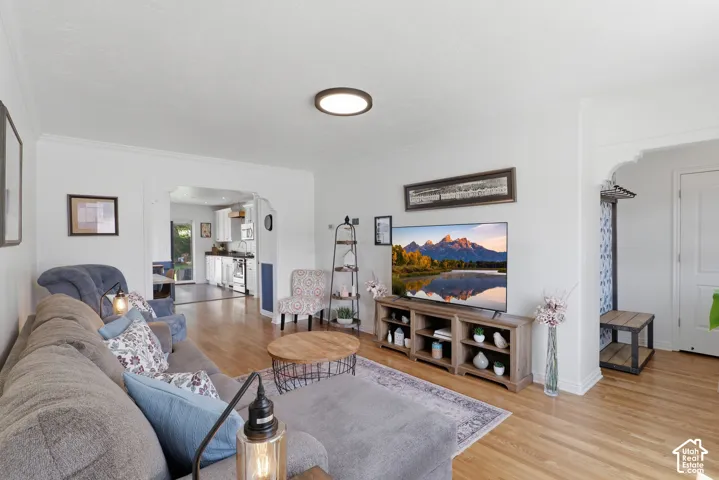 Living area with wood-finish flooring, white walls, and crown molding