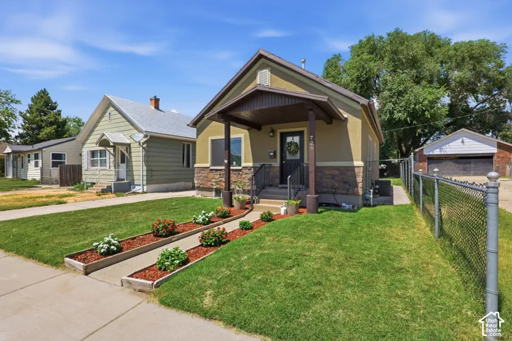Exterior featuring a covered front porch, stucco siding, and stone veneer accents