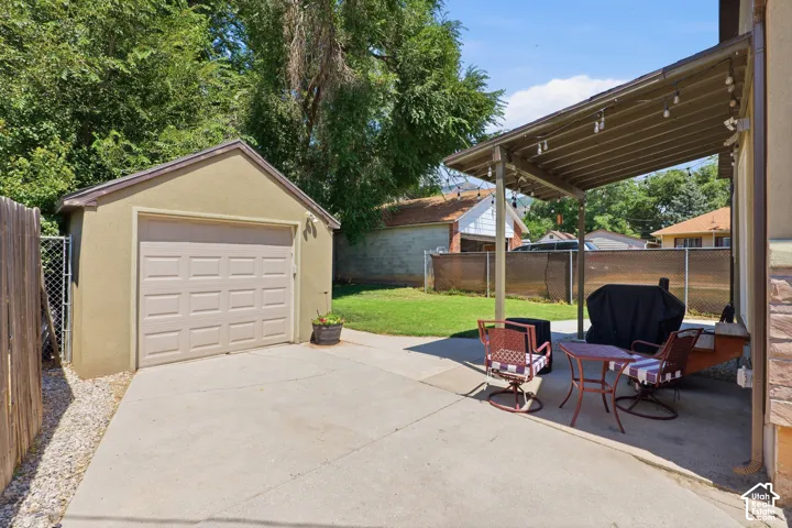 Expansive concrete patio with a covered outdoor area, adjacent to a detached garage