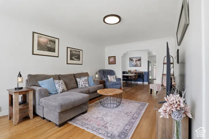 Living area featuring wood-finish flooring, white walls, and crown molding