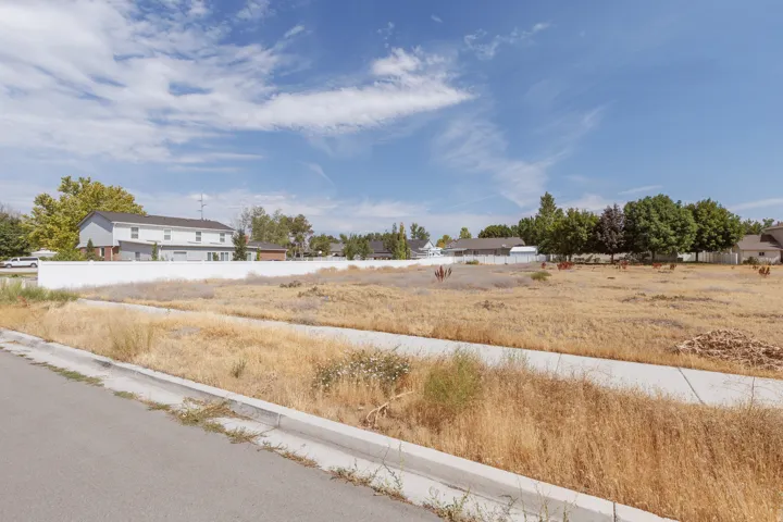 Expansive undeveloped lot featuring a concrete sidewalk and curb