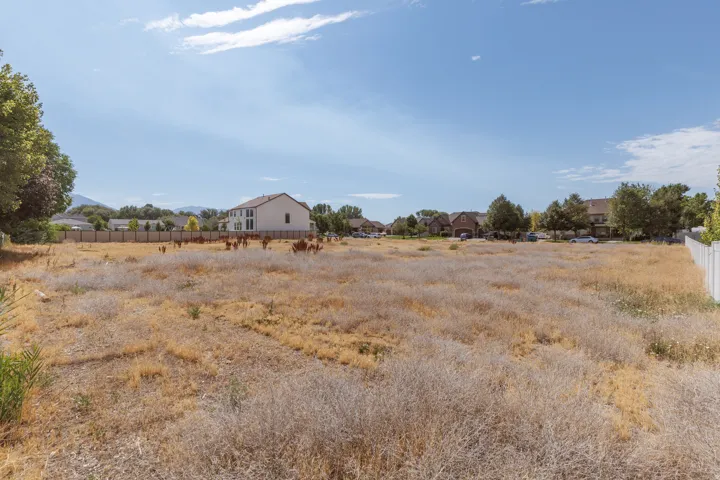 Expansive undeveloped parcel featuring a perimeter fence and distant mountain backdrop