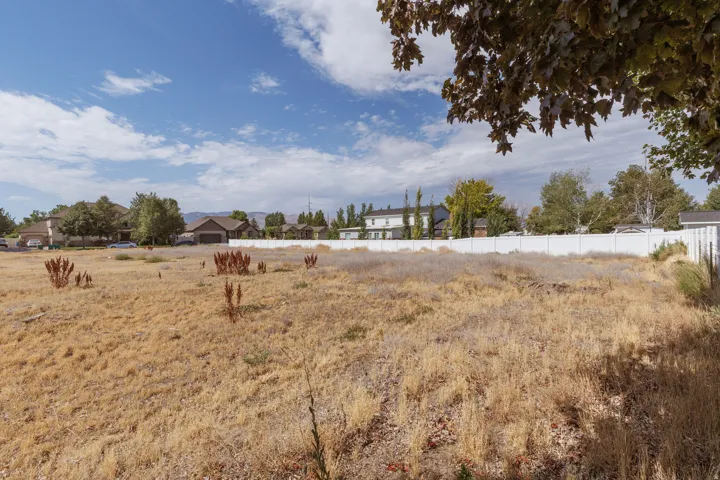 Expansive residential lot featuring a white privacy fence and established neighborhood surroundings