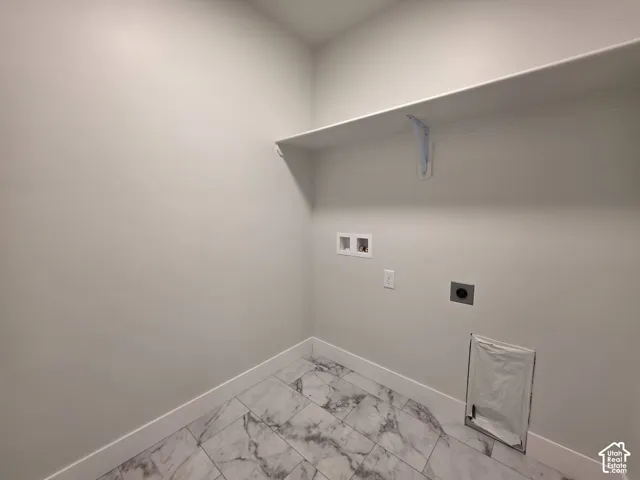 Utility room featuring white walls, a built-in shelf, tiled flooring, and laundry hookups