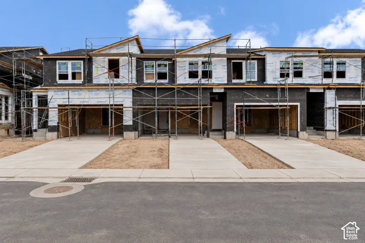 New construction townhomes featuring modern architectural lines, multiple windows, and individual concrete driveways