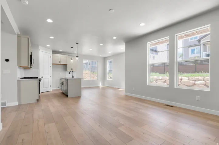 Open-concept living space featuring wood-finish flooring, recessed lighting, and large windows