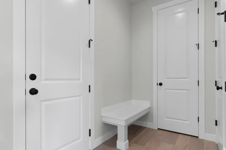 Entryway featuring light wood-finish flooring, white paneled doors with matte black hardware, and a built-in white bench