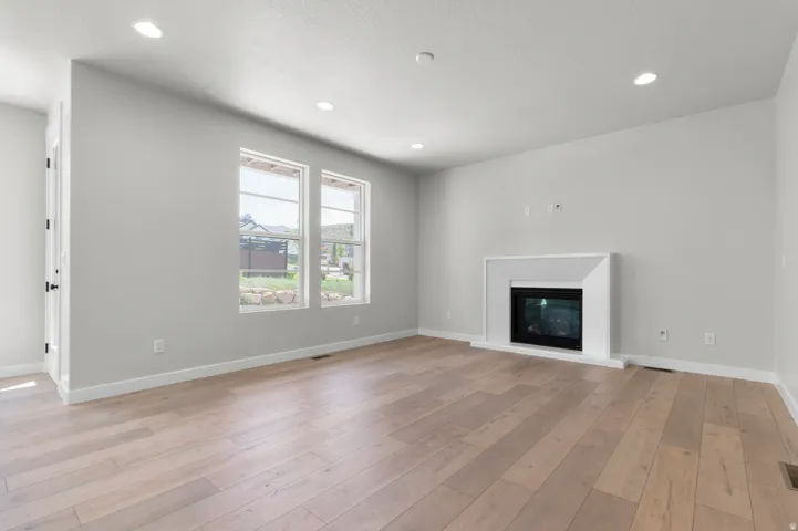 Spacious room featuring wood-finish flooring, a modern fireplace with a white surround, and recessed lighting