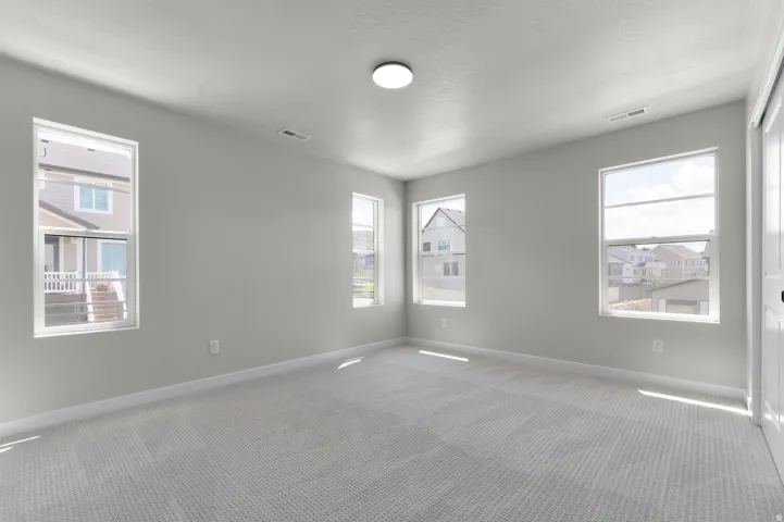 Bright room featuring multiple windows, neutral tone walls, and soft patterned carpeting