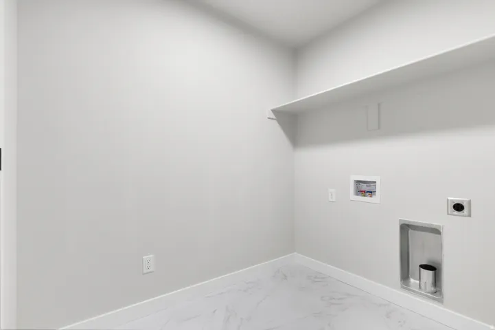 Dedicated laundry space featuring a built-in wall shelf and white marble-look flooring