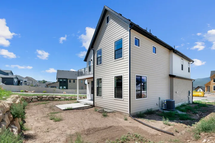 Modern exterior featuring light-colored siding, black-framed windows, and a second-story balcony with metal railing