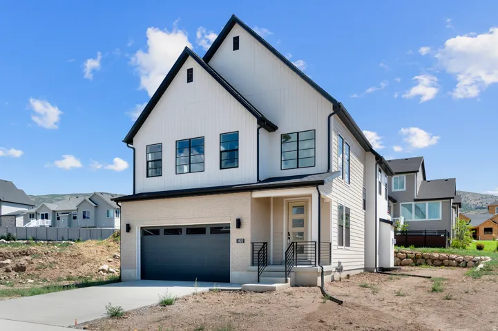 Modern farmhouse-style home with vertical white siding, black trim, and a light-colored brick facade
