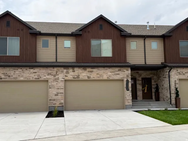 Townhome exterior featuring a stone facade and vertical wood-finish siding