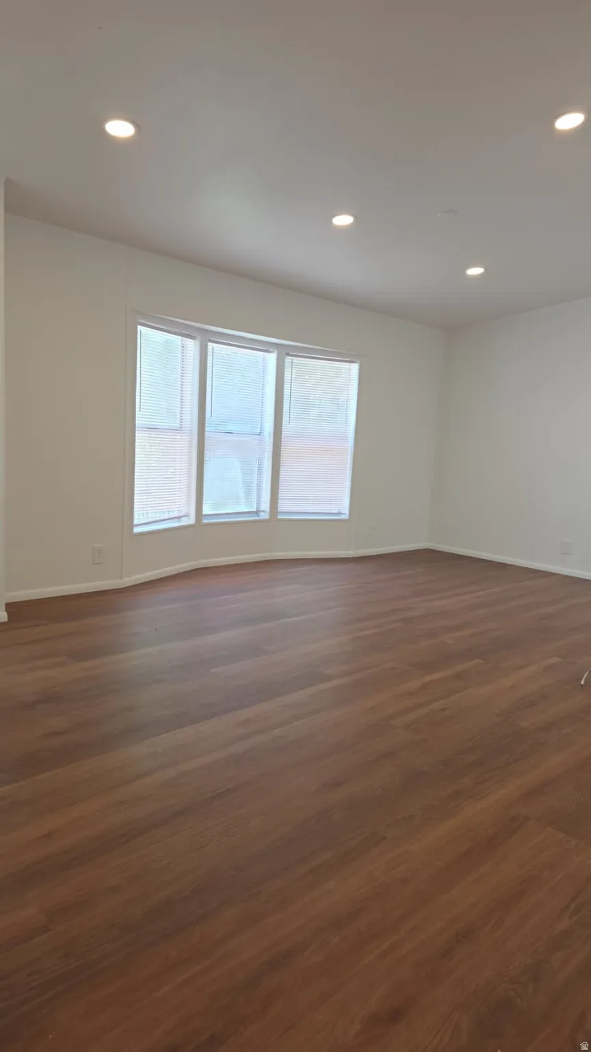 Spacious room featuring wood-finish flooring, recessed lighting, and a bay window with three vertical panes