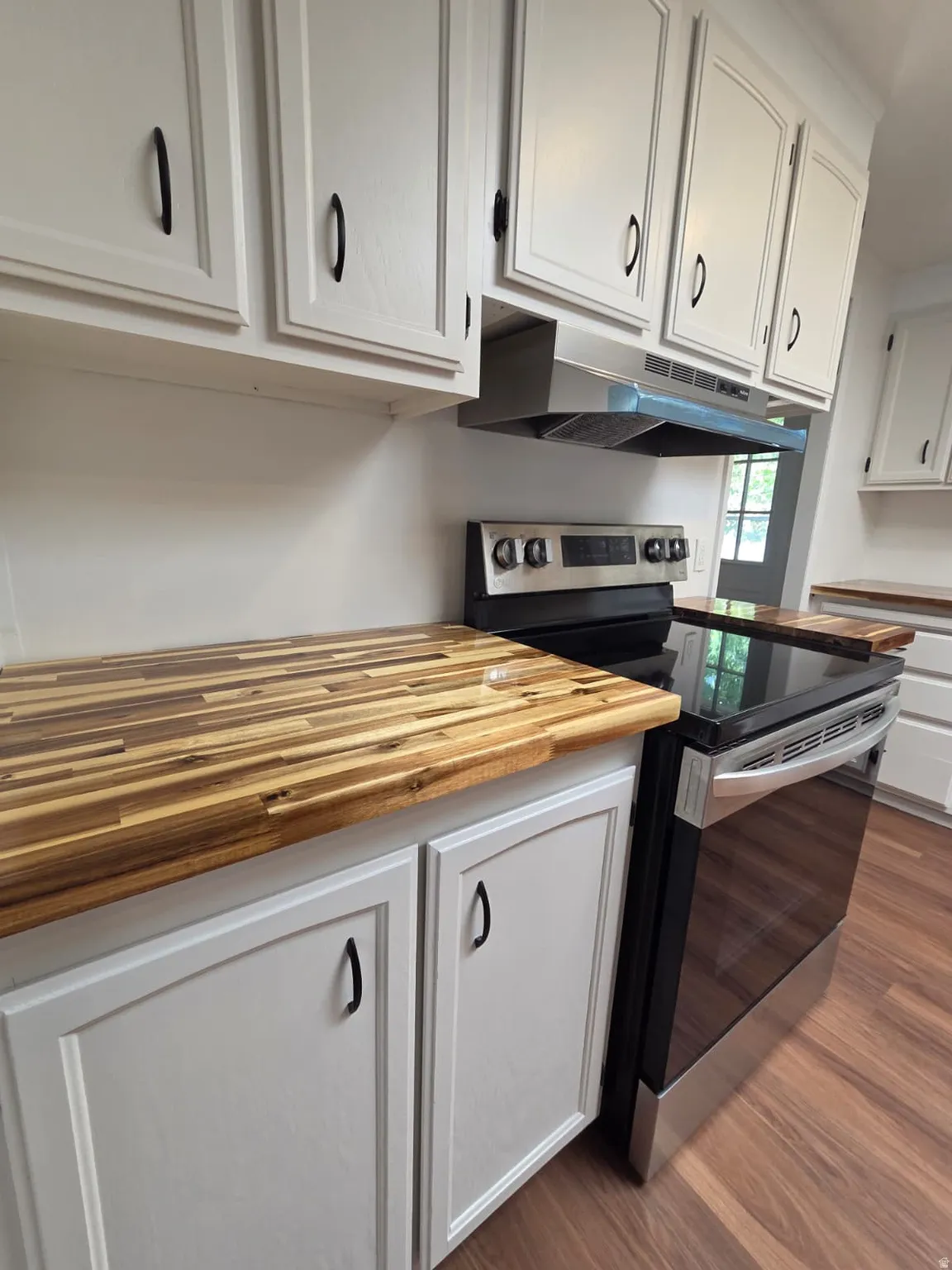 Butcher block style countertops paired with white cabinetry featuring black pulls