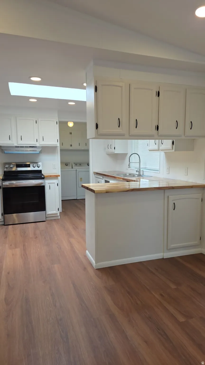 Kitchen featuring wood-finish flooring, white cabinetry with dark hardware, a stainless steel range, and butcher block-style countertops