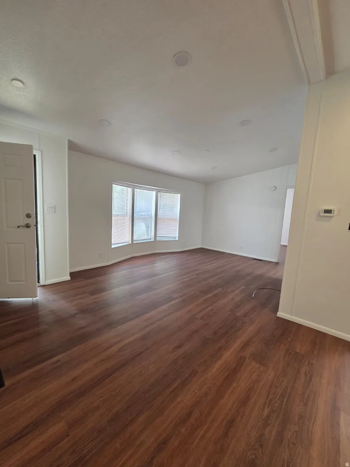 Spacious interior with flooring, white walls, recessed ceiling lighting, and a bay window