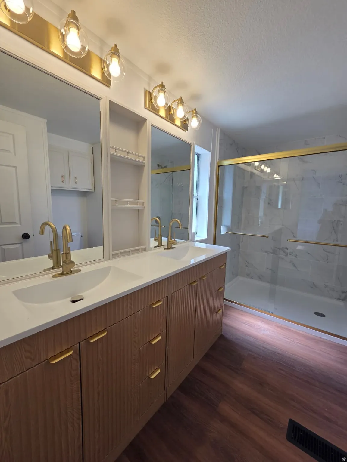 Dual vanity featuring a white countertop, under-mount sinks, and gold-finish fixtures