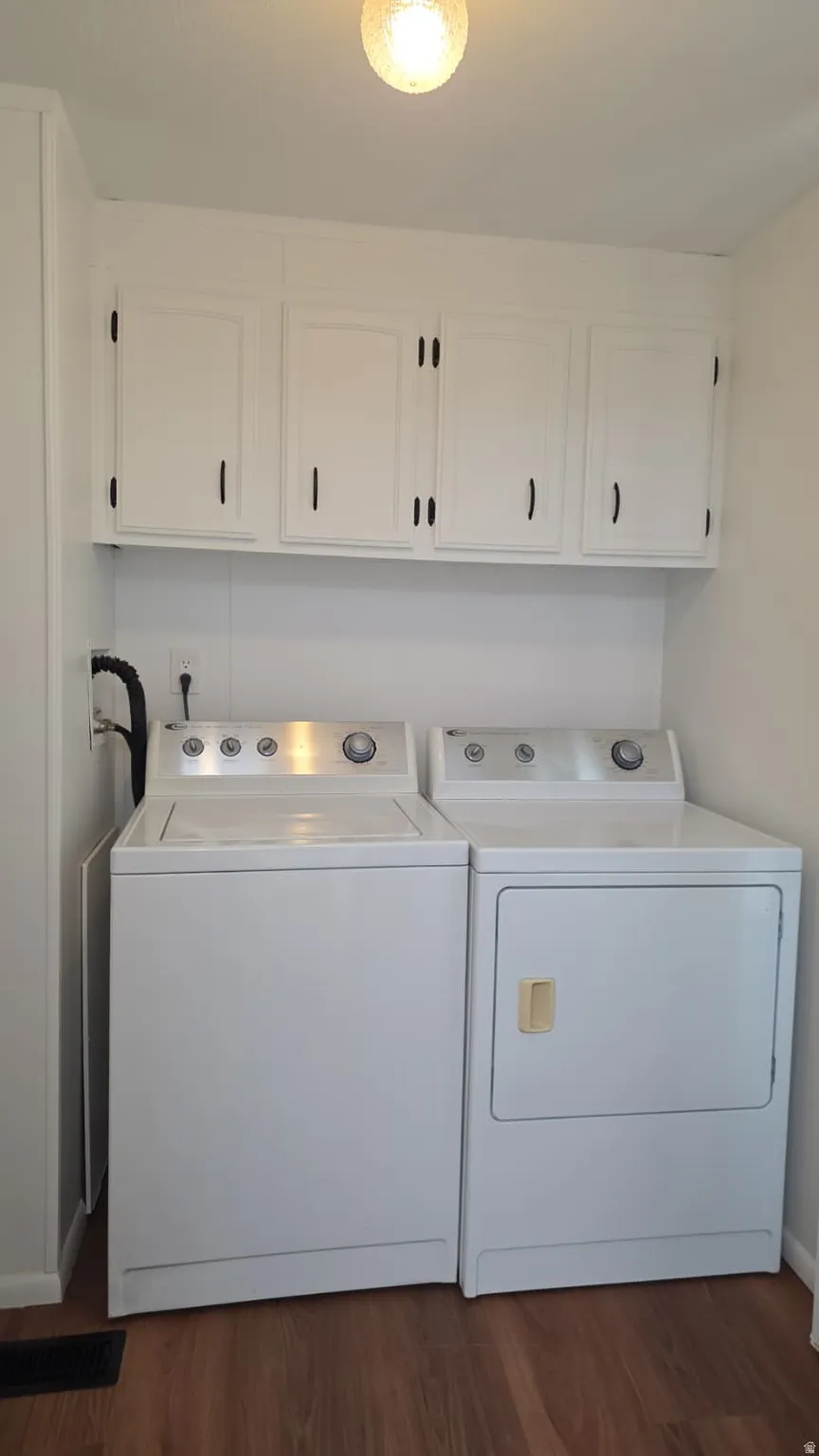 Dedicated utility area featuring wood-finish flooring, overhead cabinetry, and a ceiling-mounted light fixture
